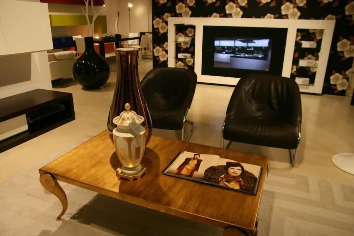 Uma sala de estar moderna com uma mesa de centro de madeira, um vaso decorativo e um quadro emoldurado.