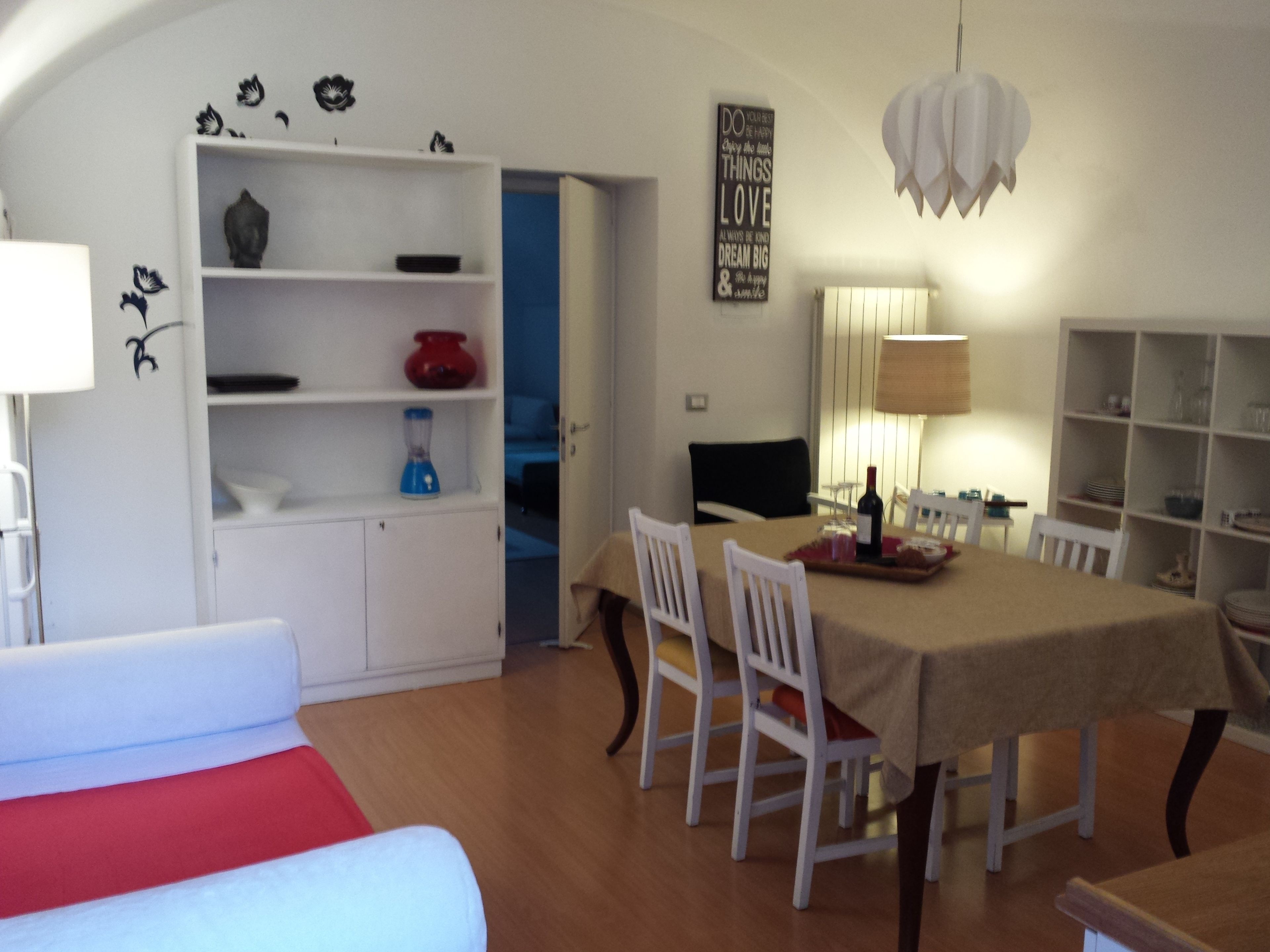 A dining area with a table, chairs, a television, and a bookshelf.