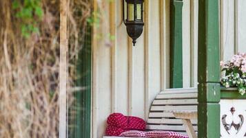 A wooden bench with a red cushion, a green post, and a wall-mounted lantern.