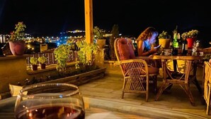 An outdoor patio with a table and chairs, a glass of red wine, and potted plants. - Avanos Suites (Avanos)