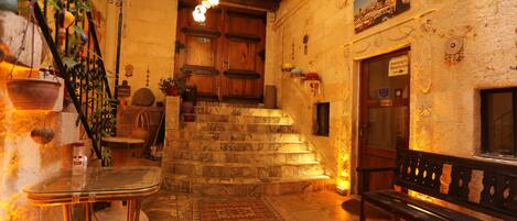 A cozy interior with a staircase leading to a wooden door, a bench, and a table with chairs.