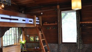 A rustic wooden room with bunk beds, a ladder, a table with towels, and a ceiling fan. - Mucumbli Hotel (Neves)