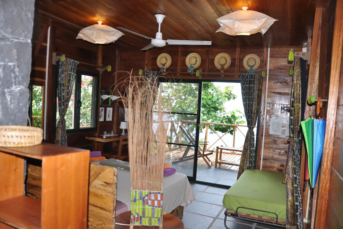 A wooden cabin interior with a bed, a table, and a ceiling fan.