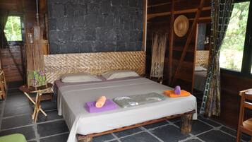 A rustic wooden room with a bed, a woven headboard, and a stone wall.