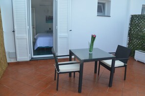 An outdoor patio with a table and chairs, a potted plant, and a sliding glass door leading to a bedroom. - B&B Il Paradiso di Capri (Anacapri)