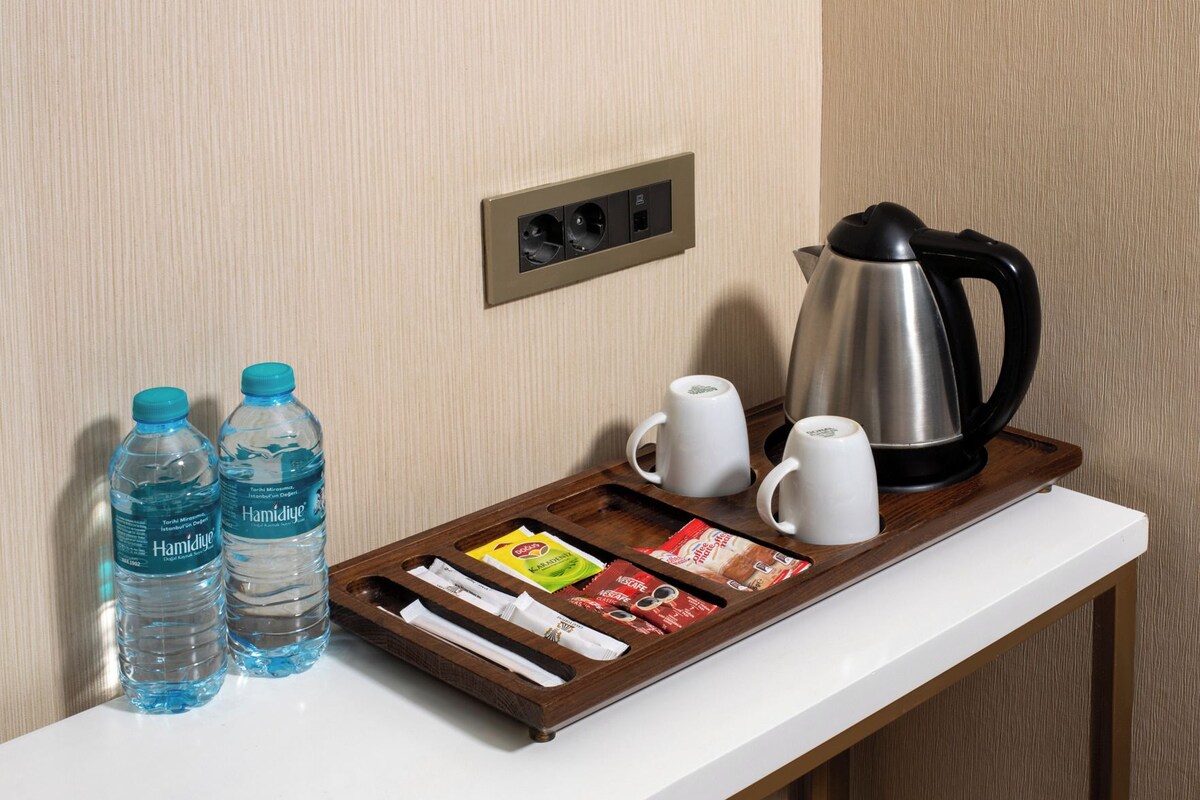 Un mini-bar dans une chambre d’hôtel, avec des bouteilles d’eau, du café et du thé.