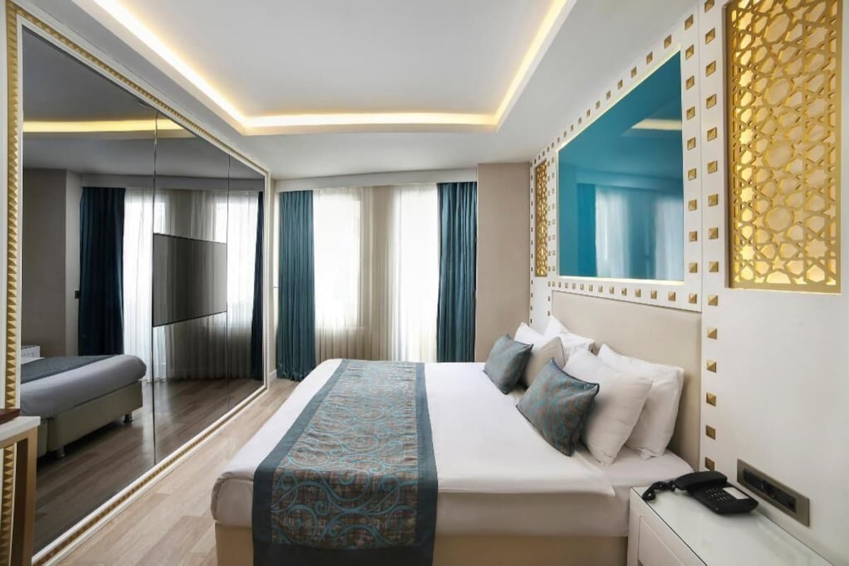 Une chambre d’hôtel moderne avec un grand lit, une télévision, une table de chevet et un miroir.