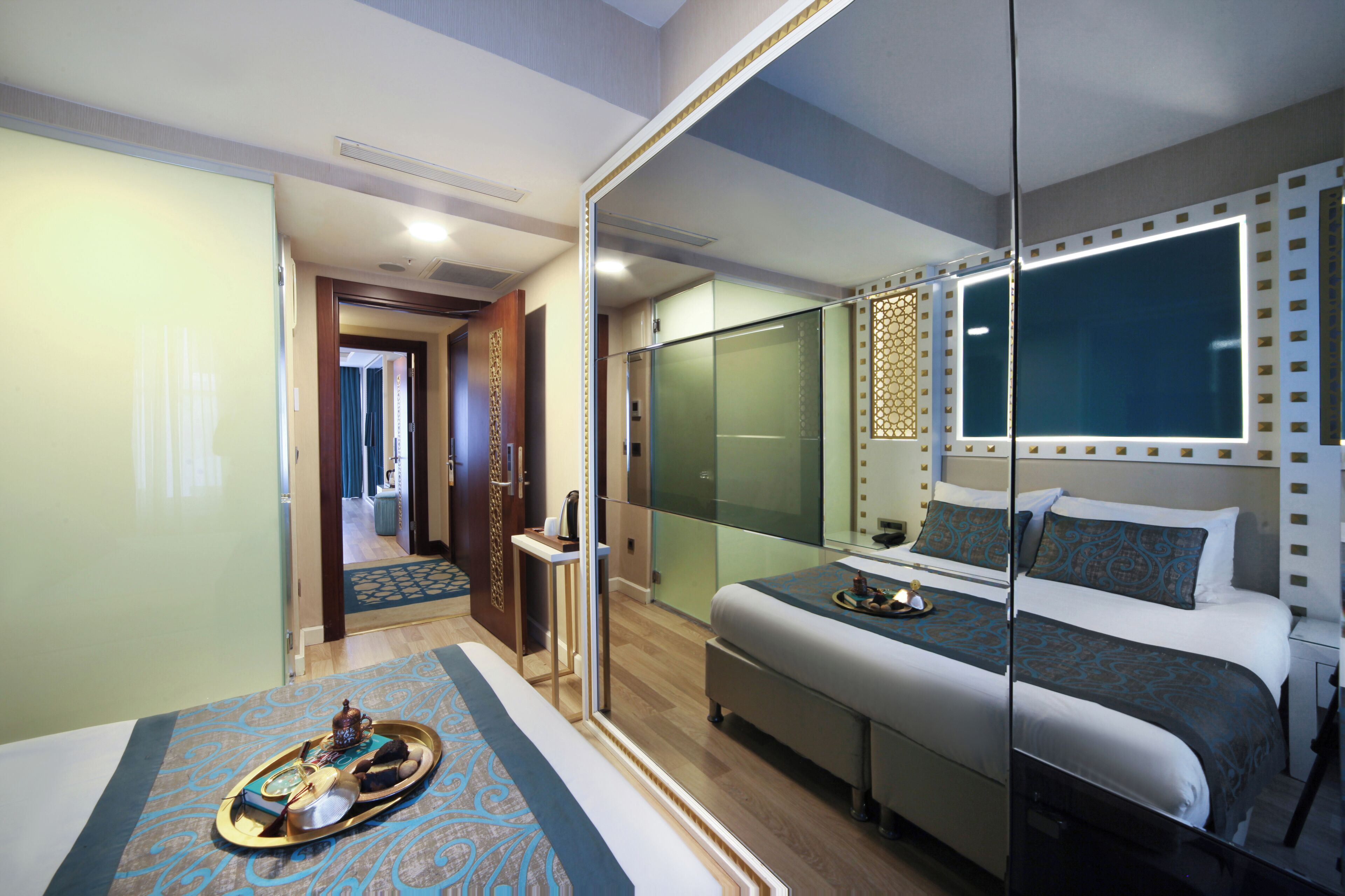 Quarto de hotel moderno com uma cama grande, um separador de vidro e uma pequena área de estar.