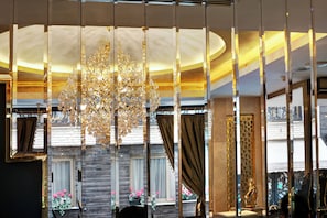 A luxurious interior with a large chandelier, elegant curtains, and a marble wall.