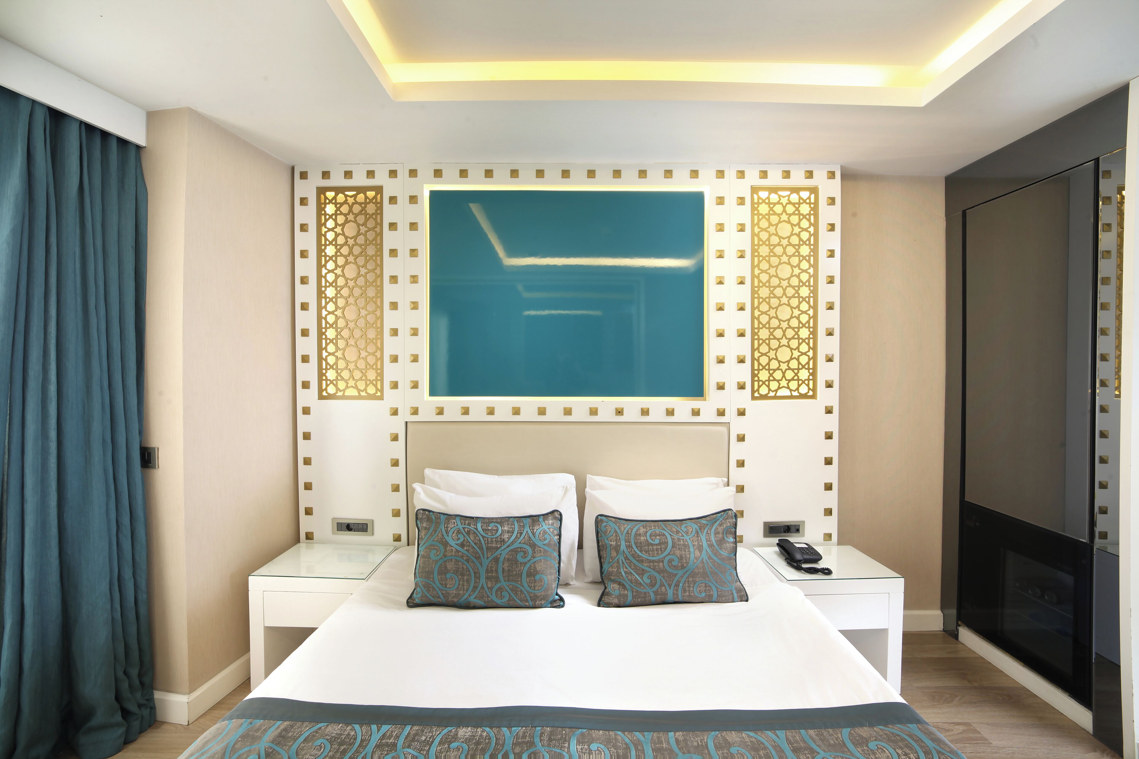 A hotel room with a bed, a TV, a nightstand, and a decorative wall panel.