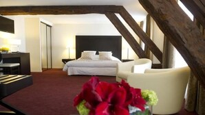 Una habitación de hotel con una cama grande, un escritorio, una silla y un florero con flores.