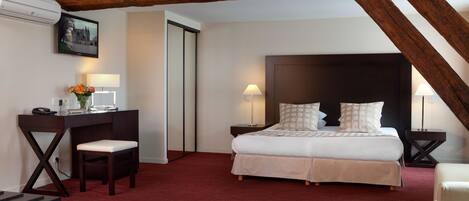A hotel room with a bed, desk, chair, and a large window.