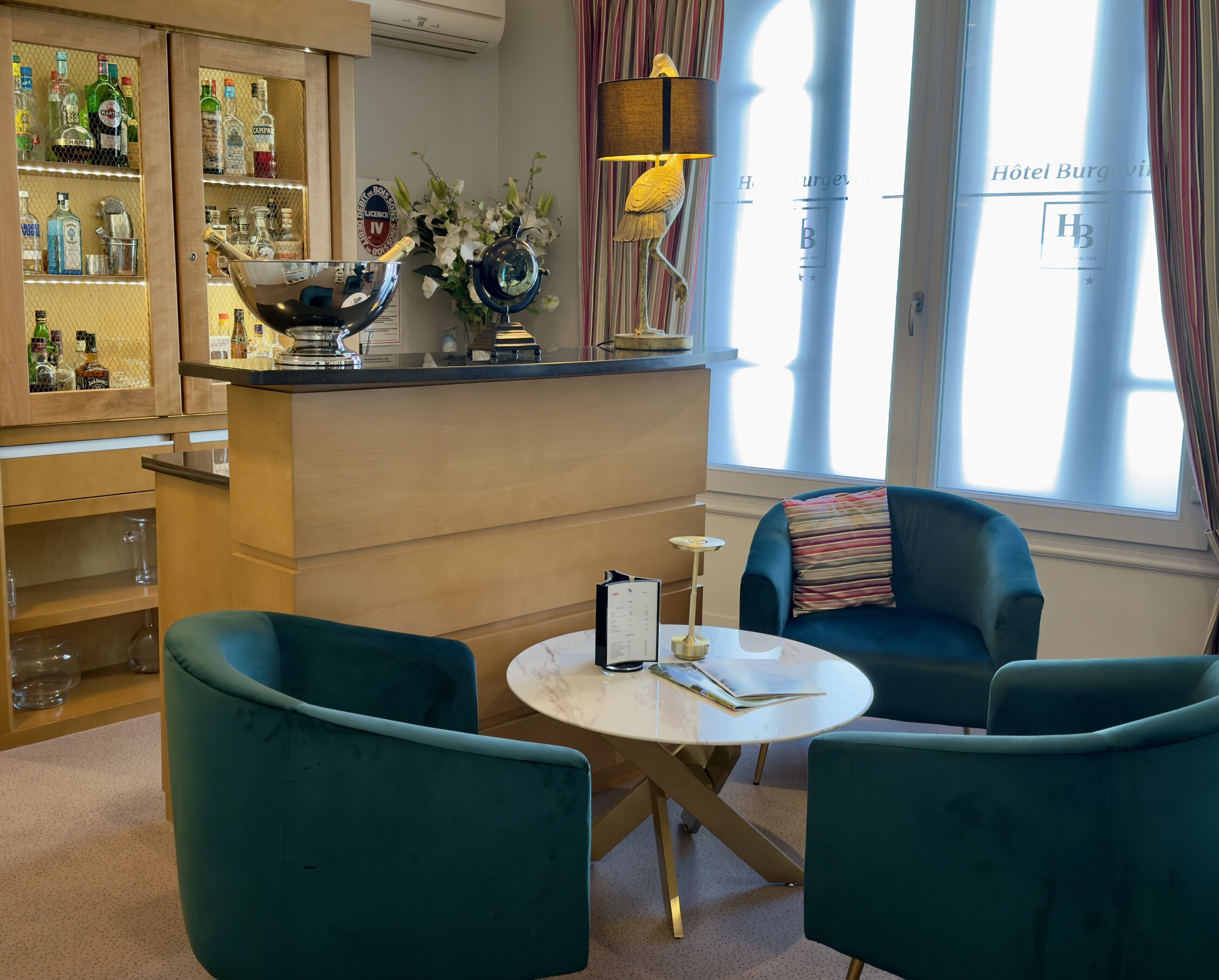 A bar area with a minibar, a round table with a menu, and a blue armchair.