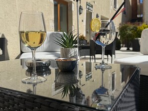 A glass table with two wine glasses, a bowl, and a potted plant.
