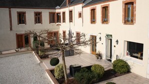 Un patio con una zona de recepción, un edificio con varias ventanas y un árbol.