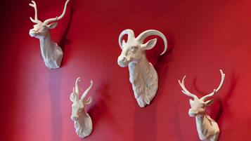 Three mounted animal heads on a red wall.