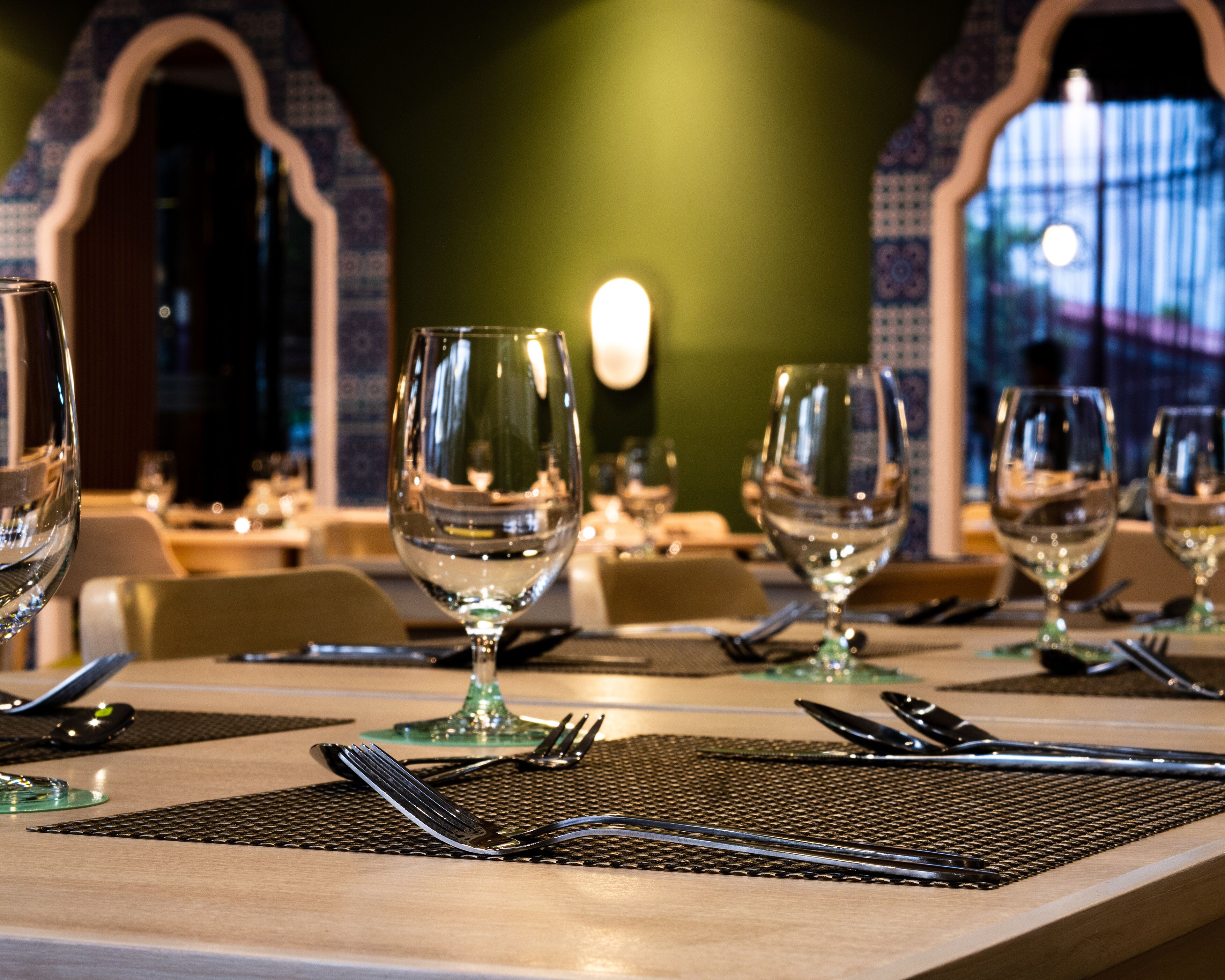A restaurant setting with tables set for dining, featuring clear glassware and cutlery.