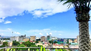 A cityscape with buildings, a palm tree, and a clear sky. - Prime Asia Hotel (Angeles City)