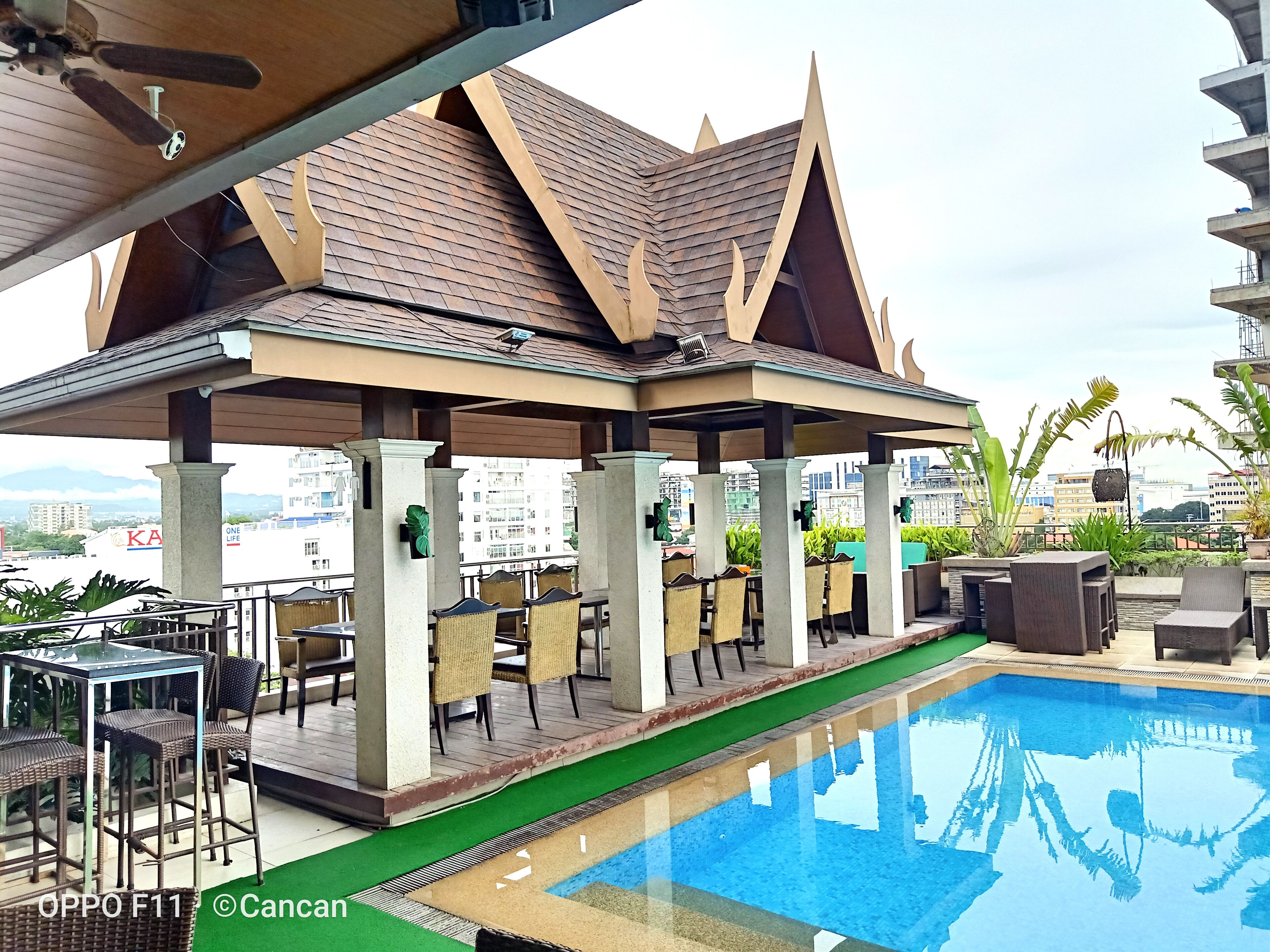 A rooftop pool area with a covered seating area and a view of the cityscape.