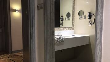 A modern bathroom with a white sink, two mirrors, a towel rack, and a hairdryer.