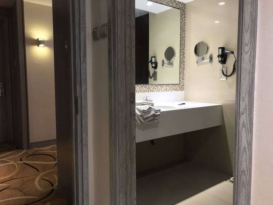 A modern bathroom with a white sink, two mirrors, a towel rack, and a hairdryer.