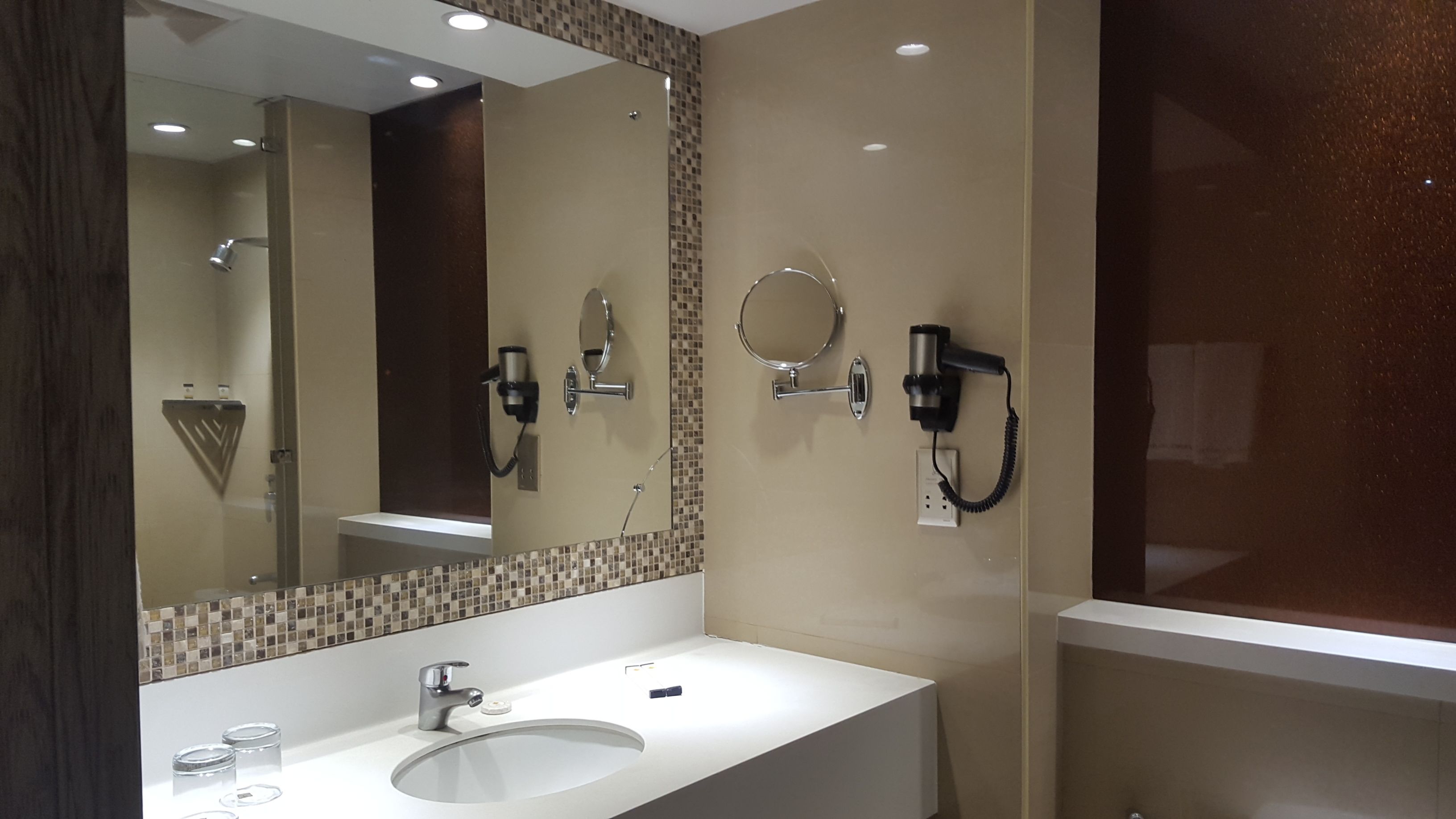 Une salle de bain moderne avec un grand miroir, un lavabo, un sèche-cheveux et un porte-serviettes.
