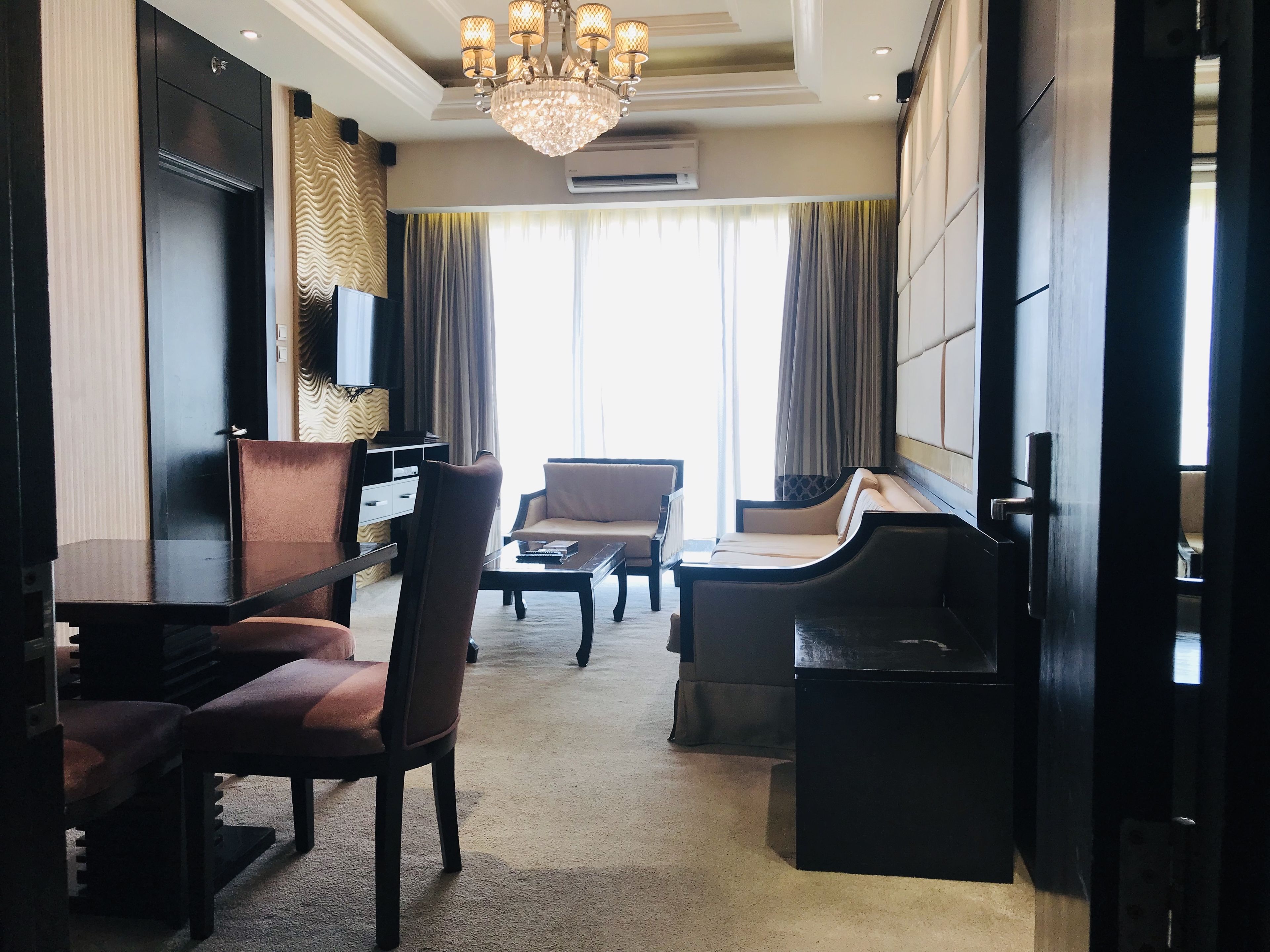 A hotel room with a large bed, a desk, a chair, a sofa, and a television.