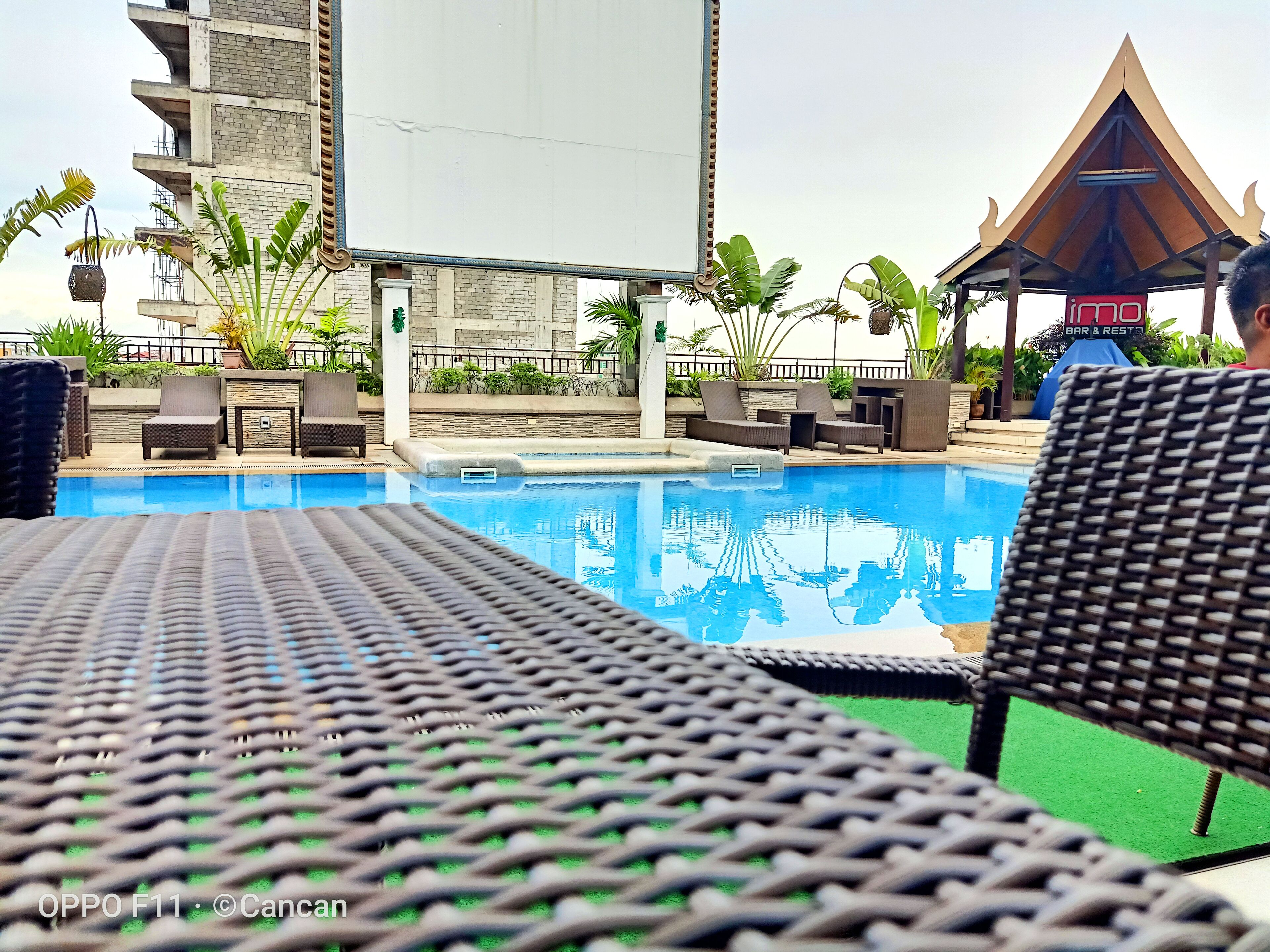 A pool area with lounge chairs and a bar & restaurant sign in the background.