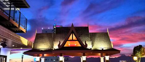 Un edificio de estilo arquitectónico tradicional, una piscina y vista del cielo al anochecer.