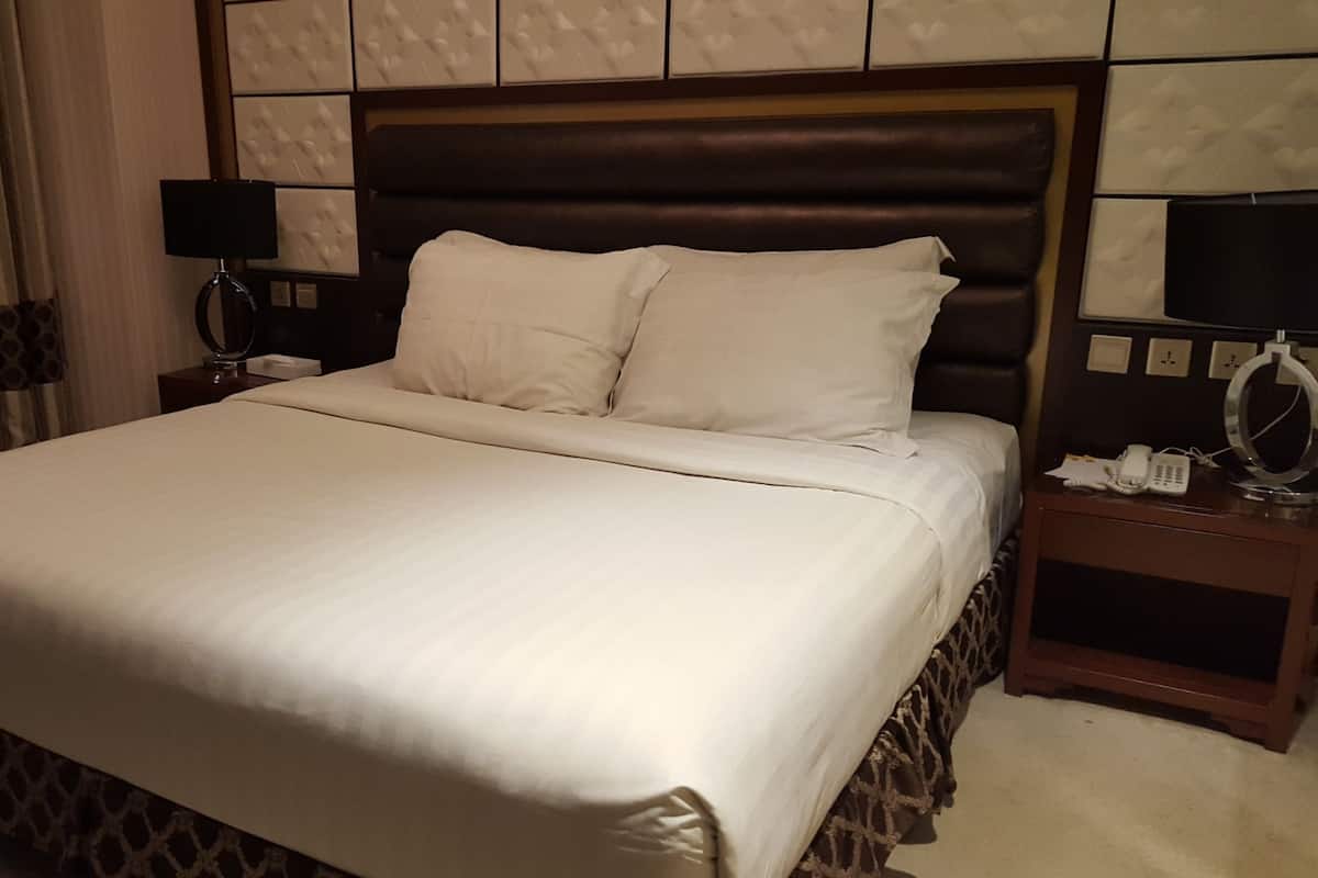 Une chambre d’hôtel avec un grand lit, une table de chevet avec une lampe et un téléphone.