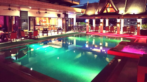 A pool area with a bar and seating, surrounded by buildings with traditional architecture. - Prime Asia Hotel (Angeles City)