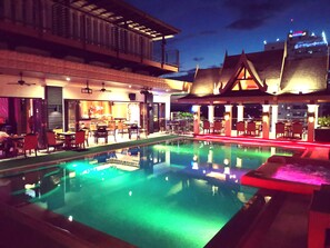 A pool area with a bar and seating, surrounded by buildings with traditional architecture.
