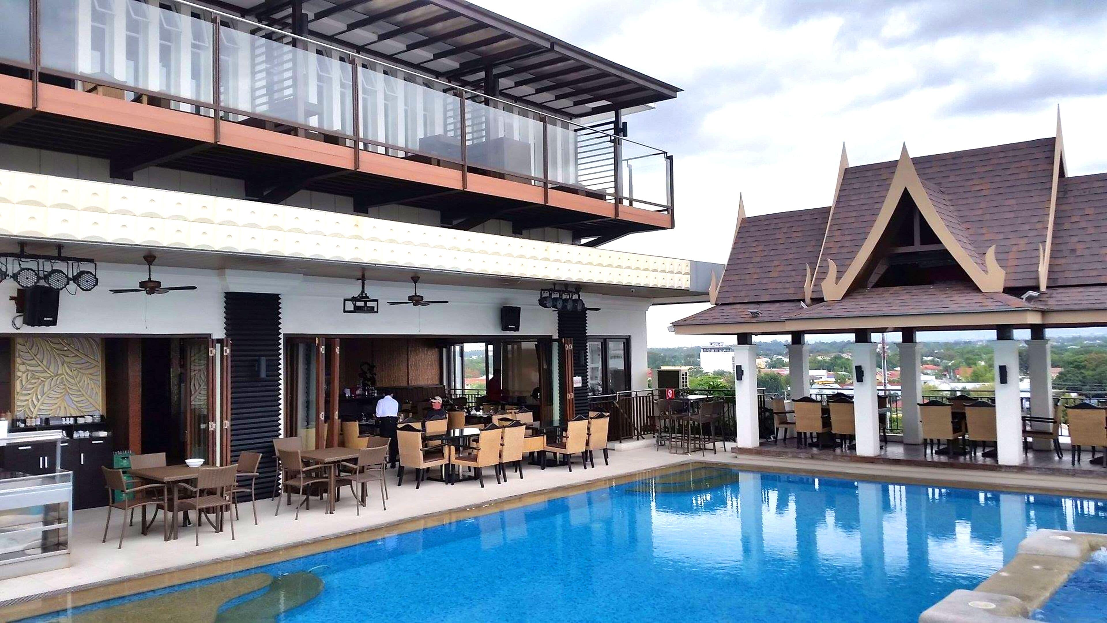 A hotel with a pool, outdoor seating, and a restaurant.
