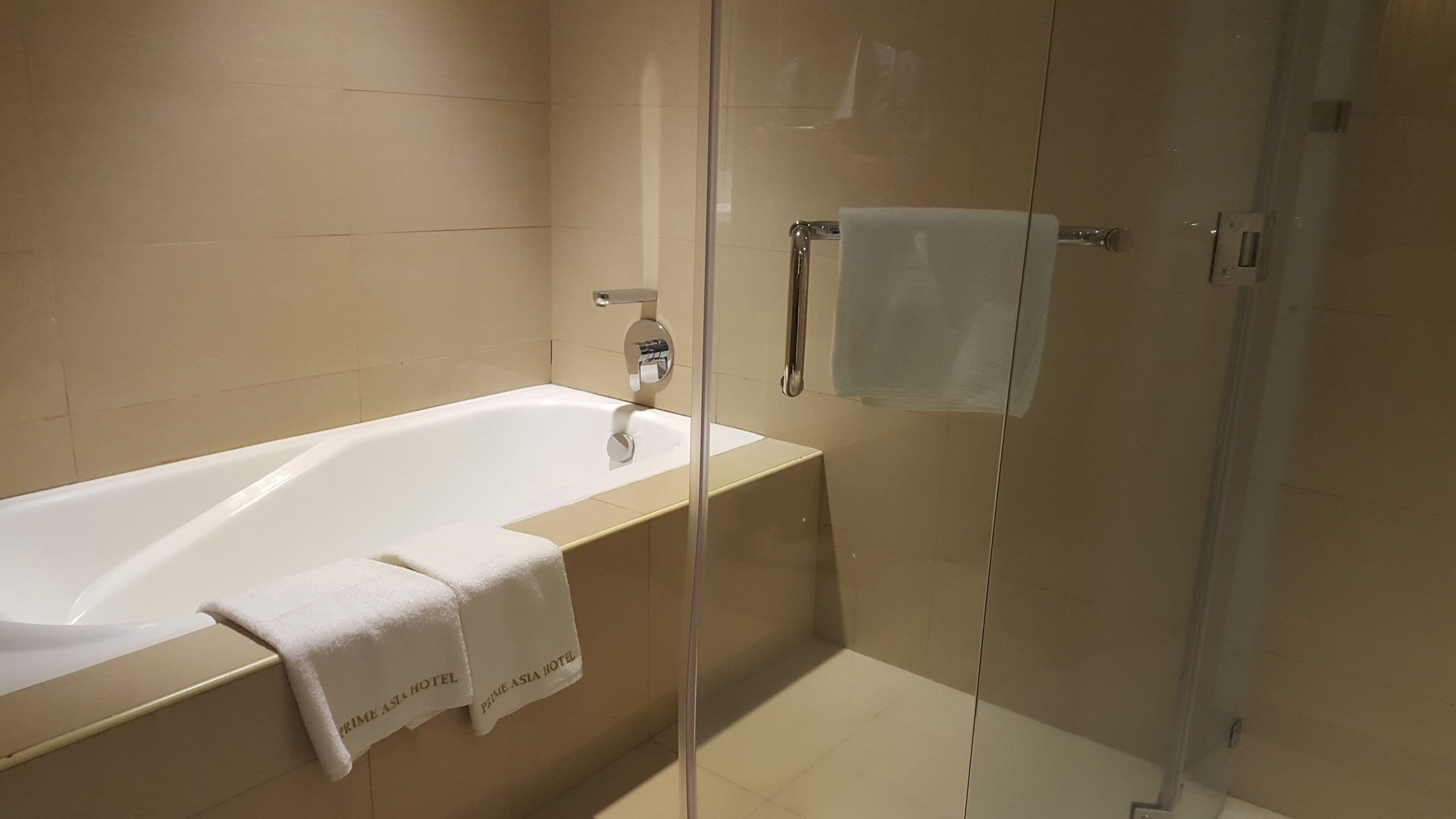 A modern bathroom with a glass-enclosed shower, a white bathtub, and a towel rack.
