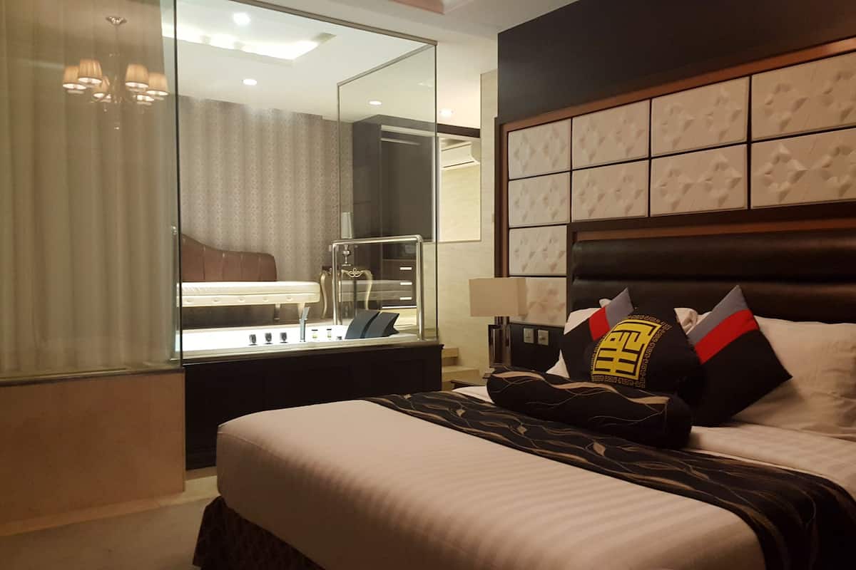 Une chambre d’hôtel avec un grand lit, une table de chevet, un miroir et un mur orné d’un motif géométrique.