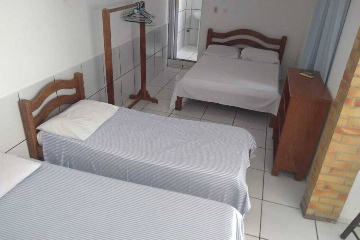 A room with two single beds, a wooden wardrobe, a mirror, and a small table.