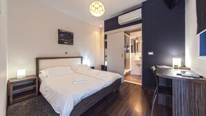 Un dormitorio moderno con una cama grande, mesitas de noche, un escritorio y una lámpara colgante.