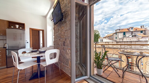 Una cocina moderna con comedor, un ventanal grande y un balcón con vistas a la ciudad.