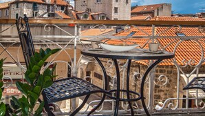 Una terraza con una mesa y sillas, una planta en maceta y vistas a edificios con tejados rojos.