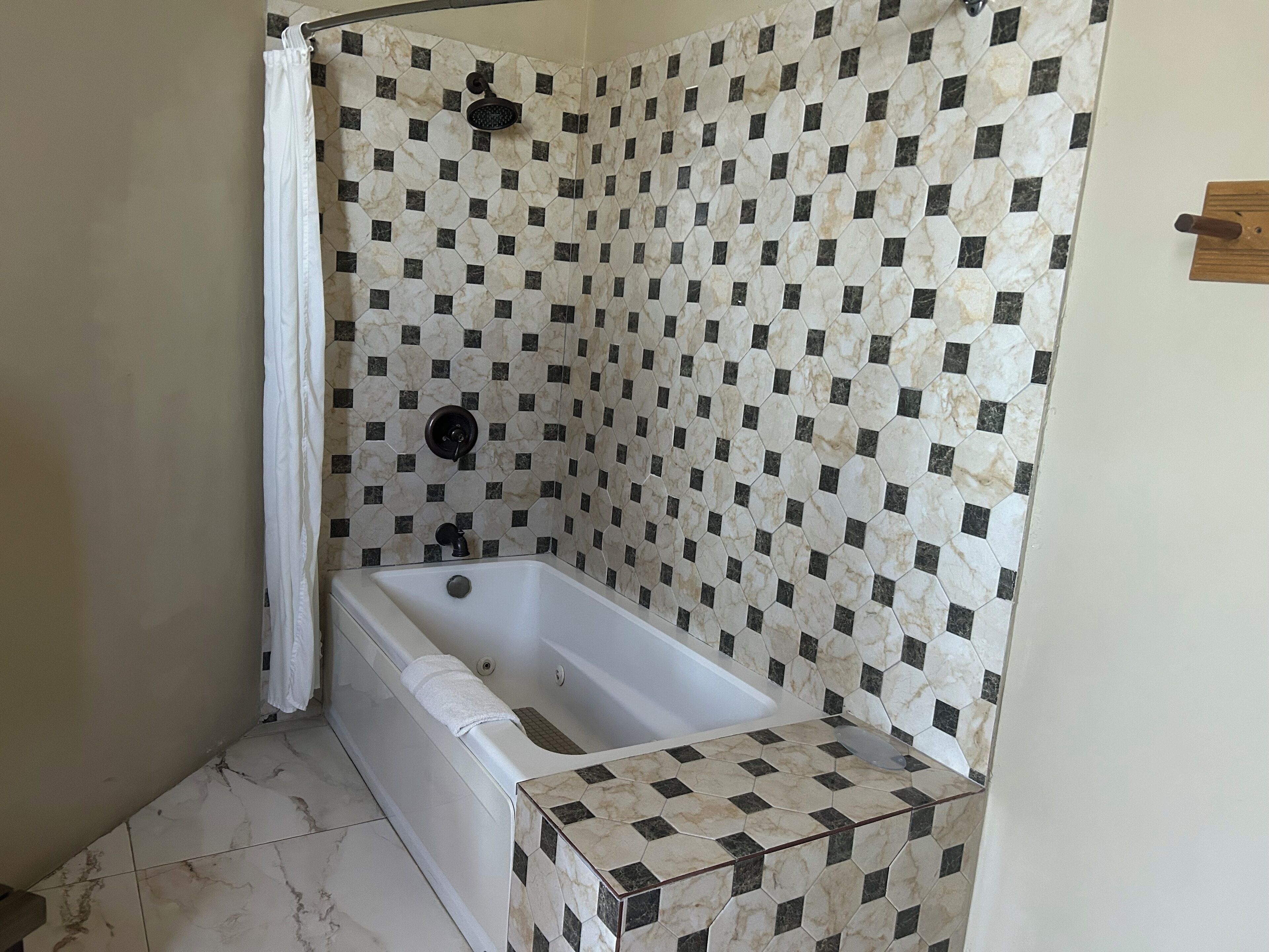 A bathroom with a shower and a bathtub, both tiled with a hexagonal pattern.