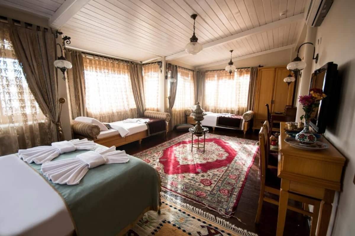 Habitació tradicional amb llit, sofà, taula de dinar i una catifes.