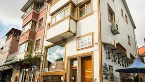 En bygning med flere etager, butik i stueplan, balkon og trappe op til indgangen.