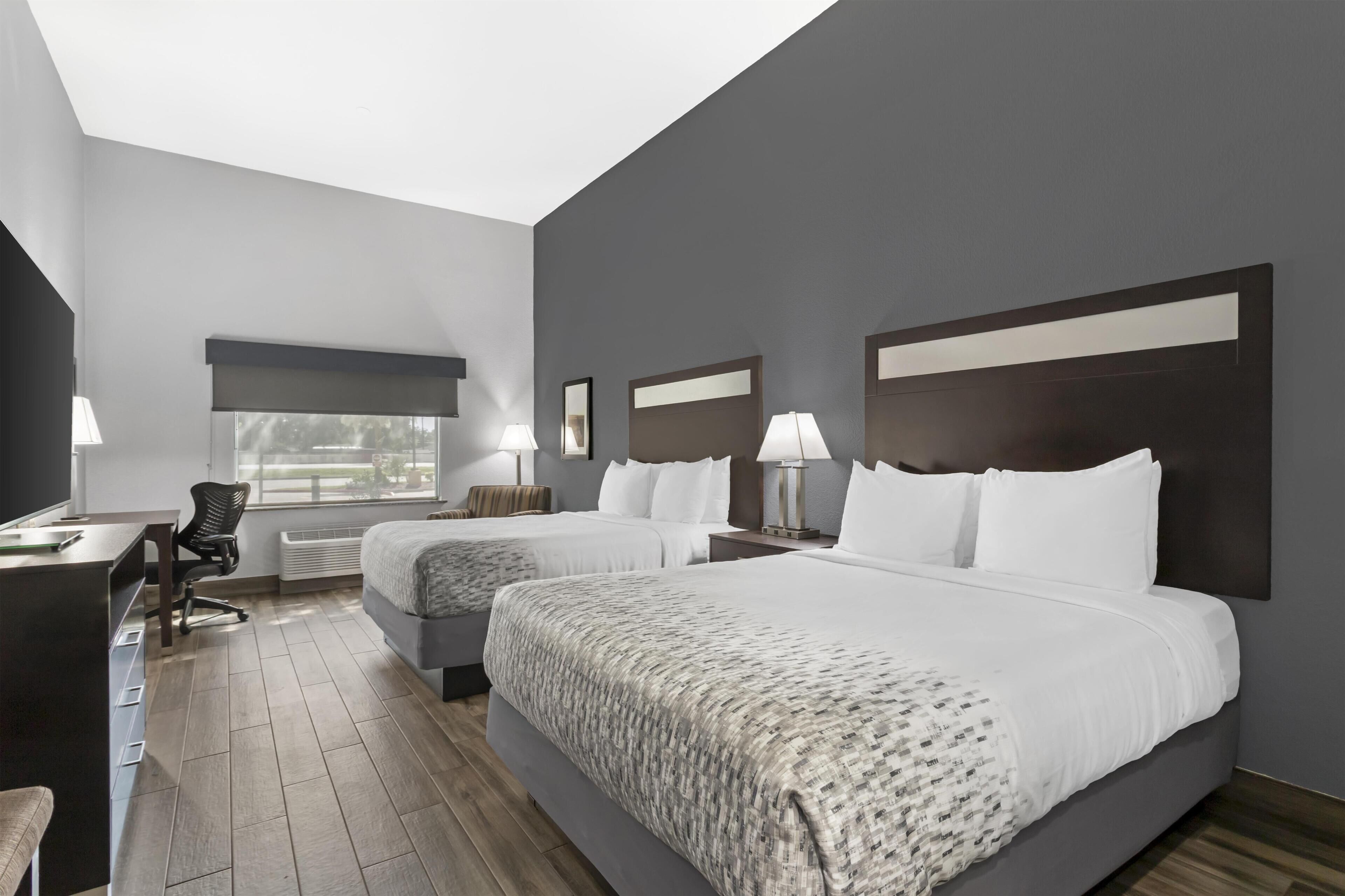 A hotel room with two beds, a desk, and a chair.