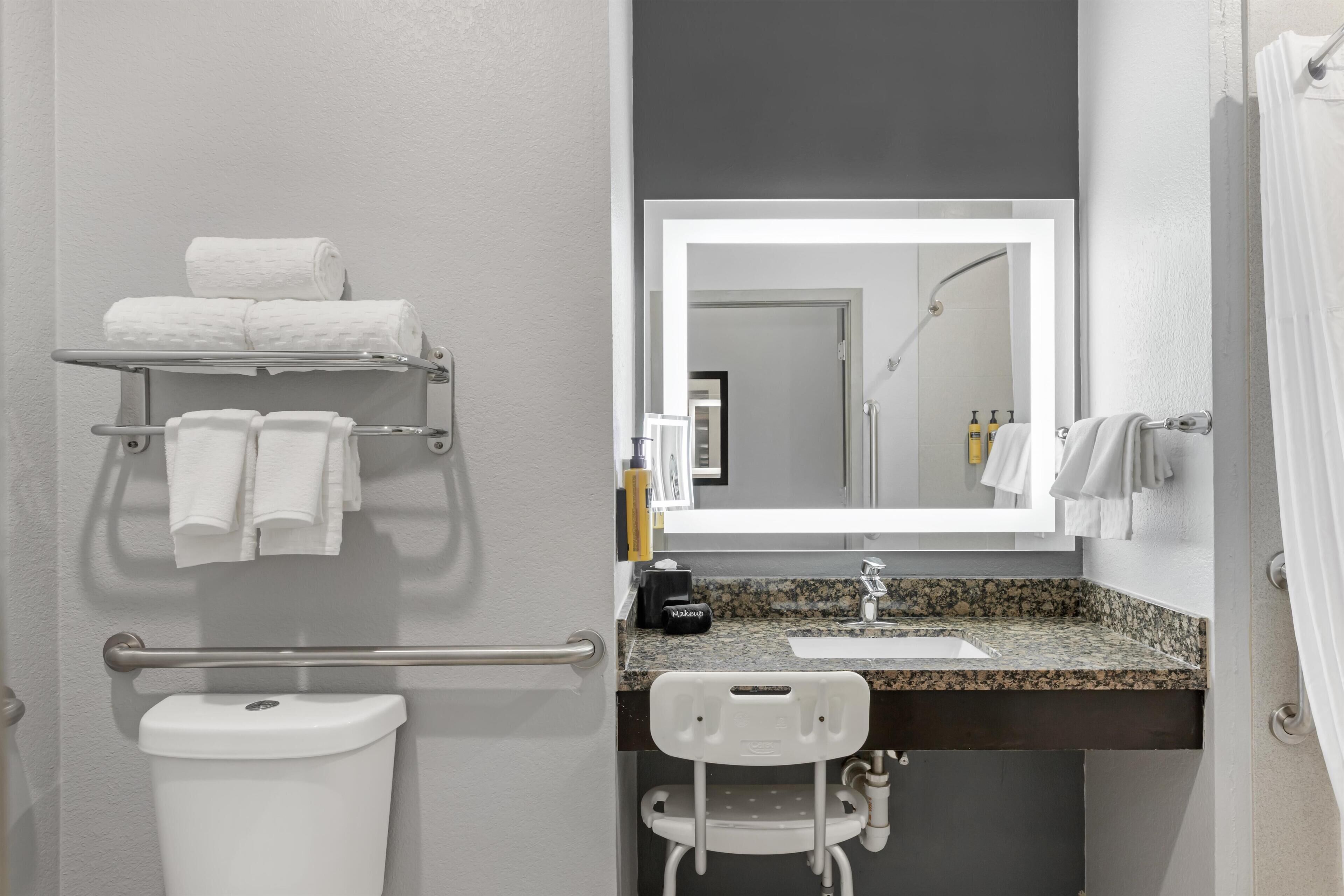 A bathroom with a toilet, a towel rack, a sink with a mirror, and a shower area.
