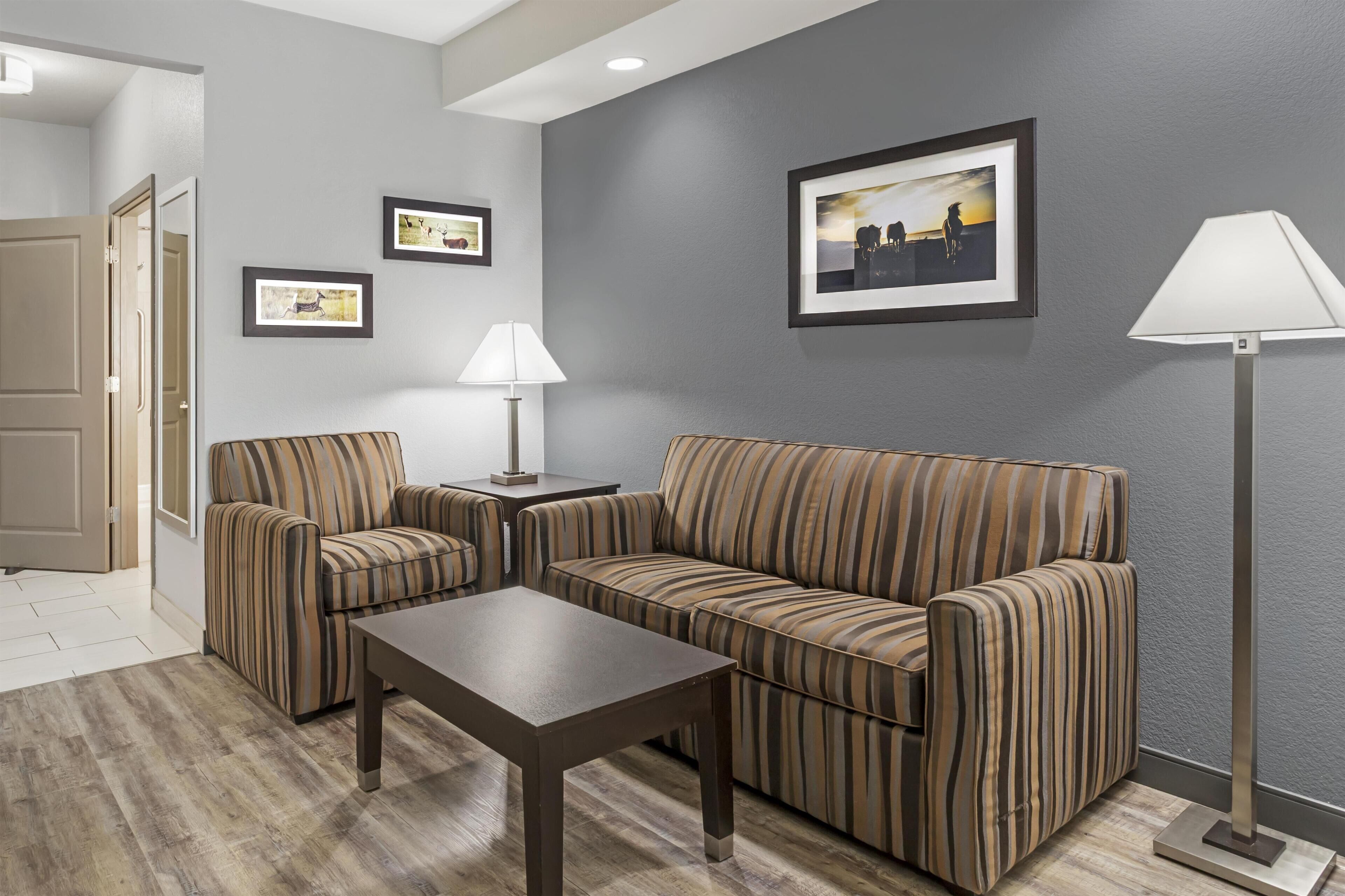 Una sala de estar moderna con un sofá, dos sillones, una mesita de centro y una lámpara de pie.