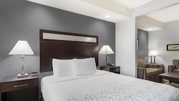 A hotel room with a large bed, two bedside tables with lamps, a chair, and a desk.