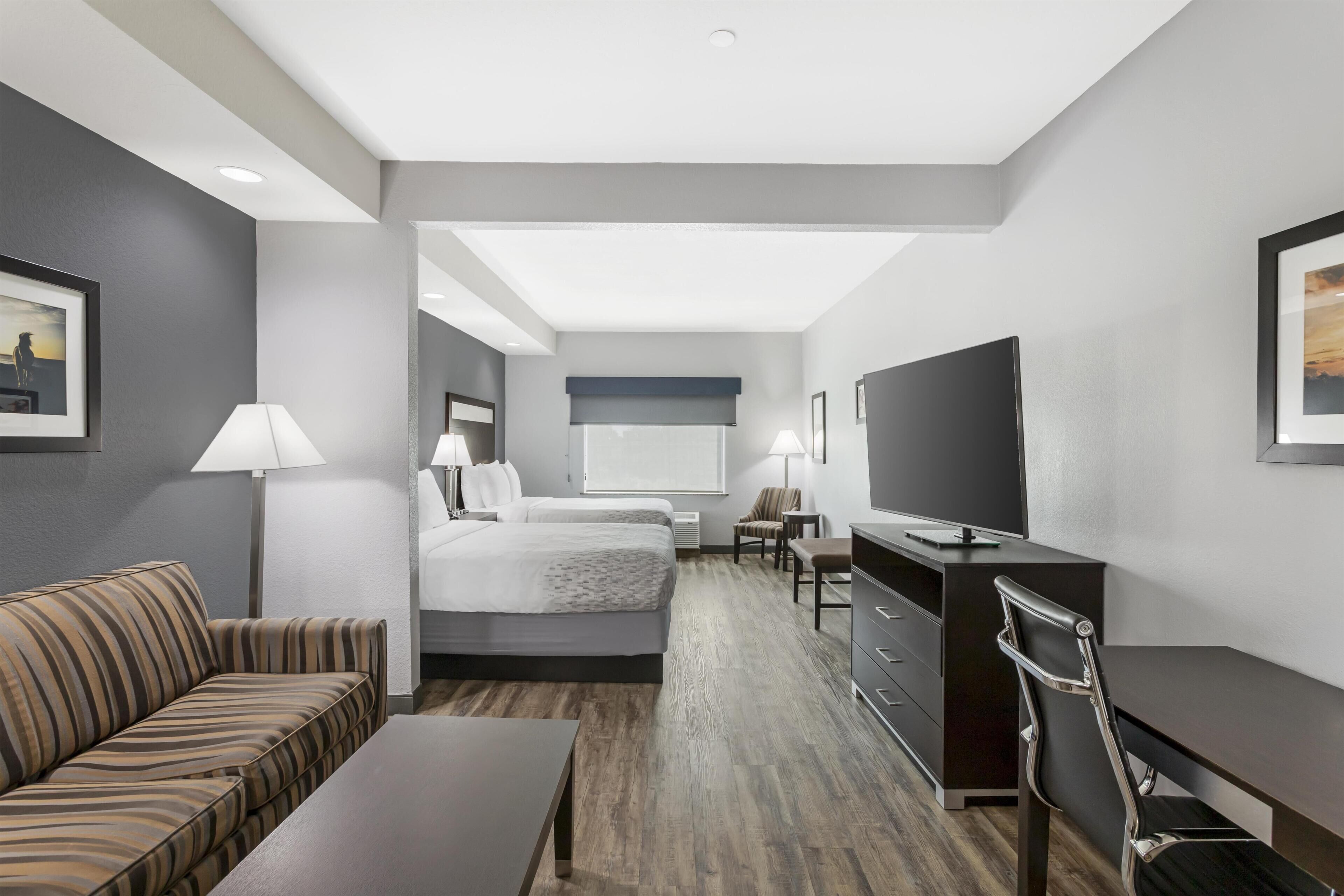Una camera d'albergo con un letto, una scrivania, una televisione, un divano e una poltrona.