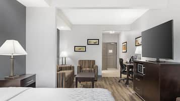 A hotel room with a bed, a desk, a chair, a television, and a lamp.