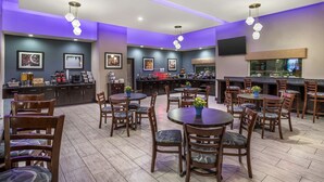 En moderne restaurant med flere spiseområder, en bar og et køkken i baggrunden.
