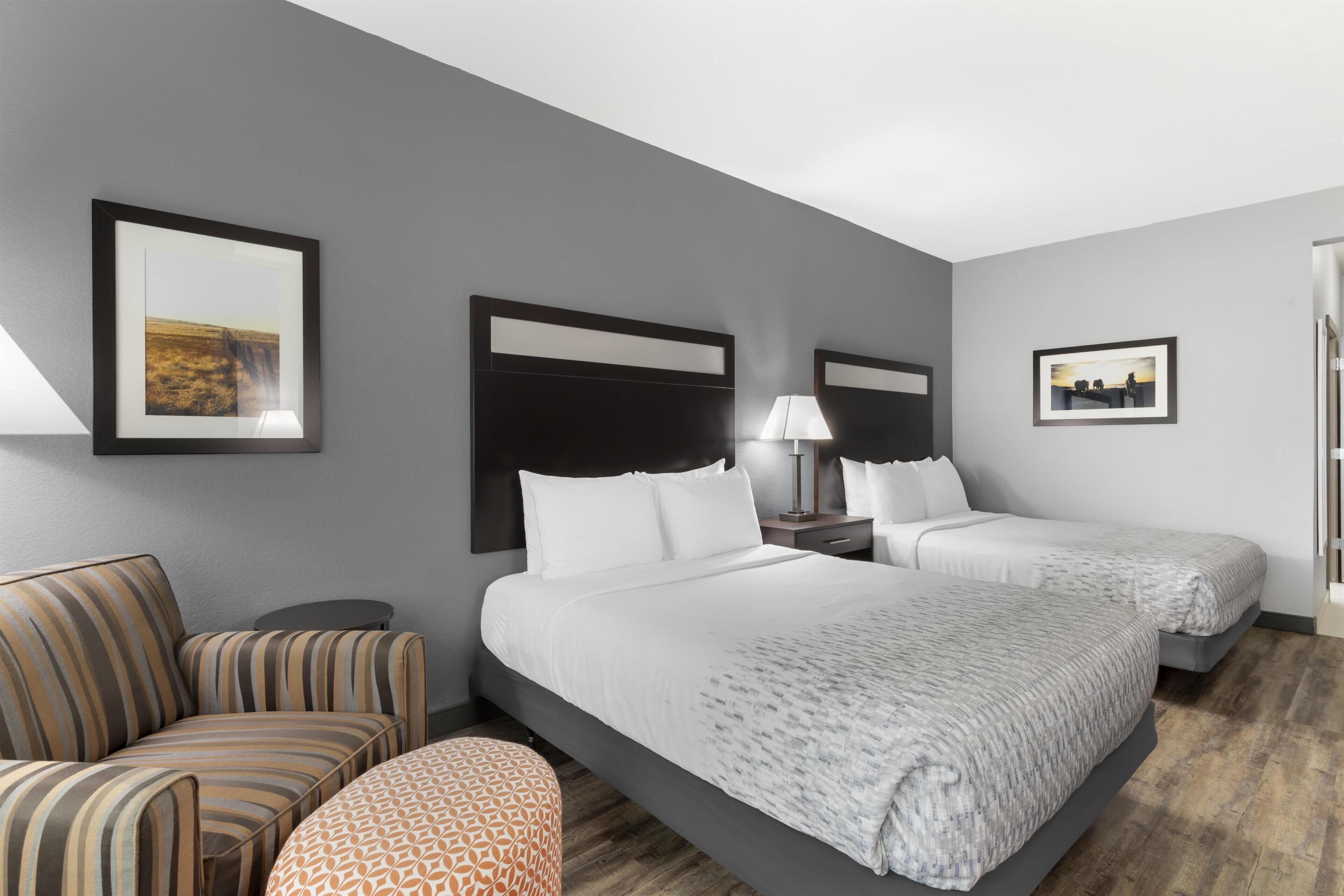 A hotel room with two beds, a sofa, a small table, and framed pictures on the walls.